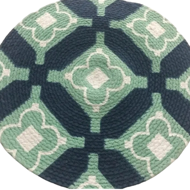 Round woven rug with geometric green, white, and dark blue patterns.