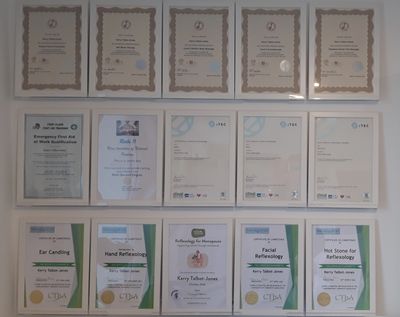 A wall with multiple framed certificates and diplomas arranged in rows.