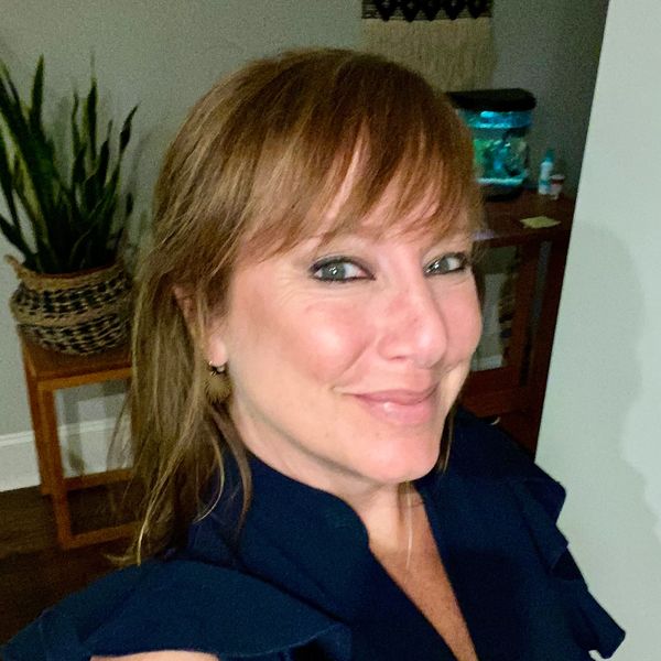 Smiling woman with light brown hair in a dark blue top.