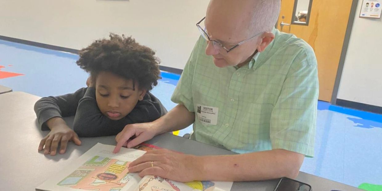 Older man reading with a young boy.
