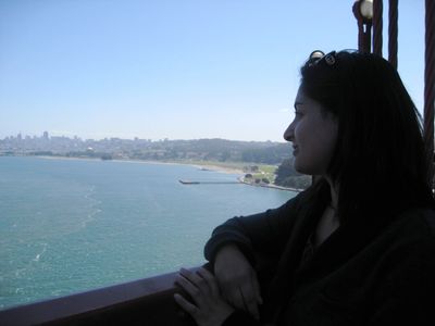 Woman looking out over a large body of water with a city skyline in the distance.