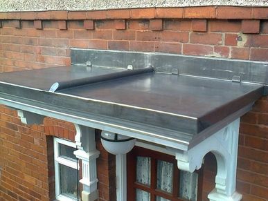 Metal canopy above a wooden door and window on a brick building.