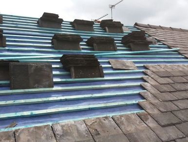 Roof under construction with wooden battens and stacked tiles.