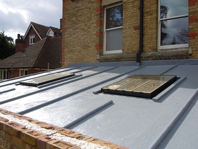 A flat rooftop with two skylights on a residential building.