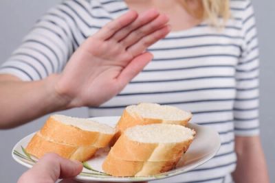 Woman refusing a plate of sliced bread with a hand gesture.