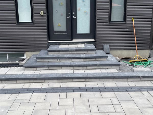 Modern house entrance with gray siding and tiled steps.