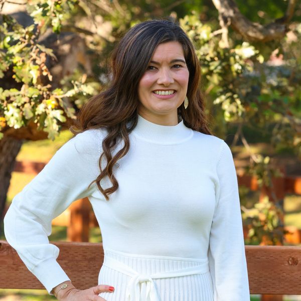Woman in white sweater smiling outdoors