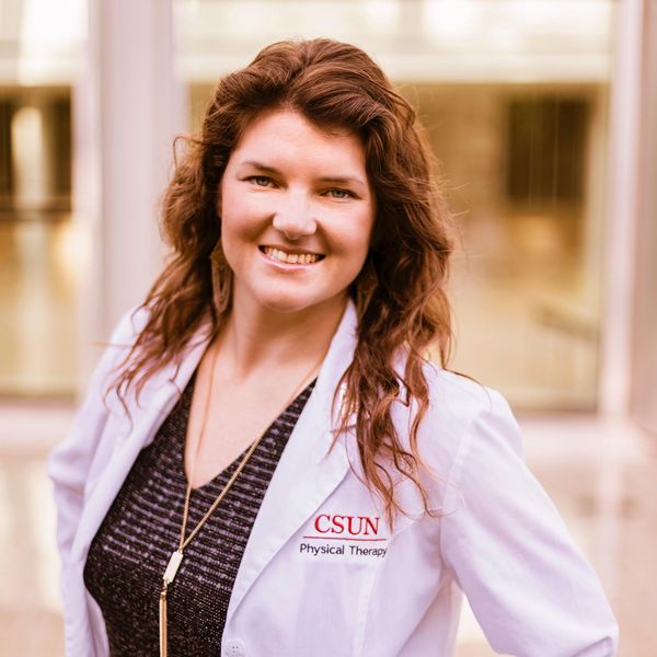 Smiling woman in a white CSUN Physical Therapy coat.