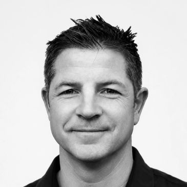 Black and white portrait of a smiling man with short hair.