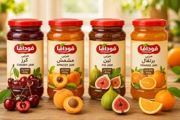 Four jars of different fruit jams on a wooden surface.