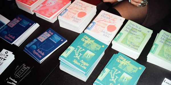 Stacks of colorful books with various titles on a black table.