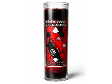 A black candle in a glass jar with a red label reading 'seven times reversible'.