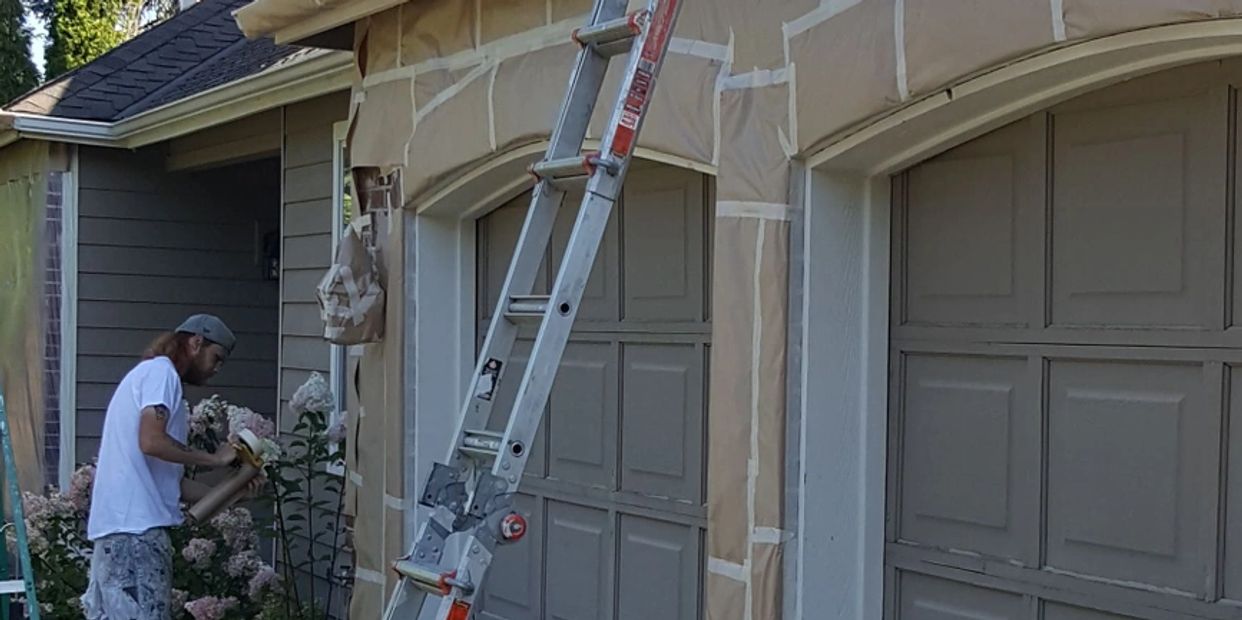 A worker preparing a garage for home painting services.