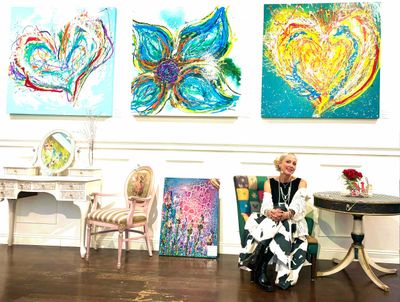 Woman sitting in an art gallery with colorful abstract paintings on the wall.