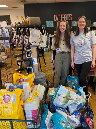 Two women standing in a pet store with a large collection of pet supplies.