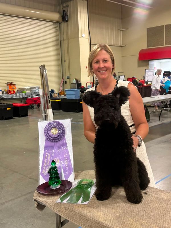 Woman with dog and dog show awards indoors.