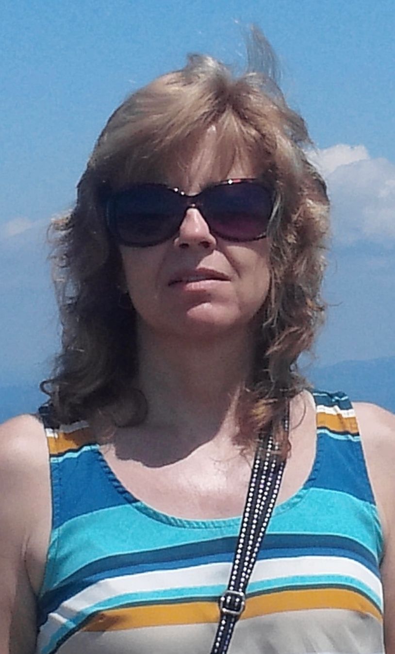 Woman wearing sunglasses and a striped tank top outside on a sunny day.