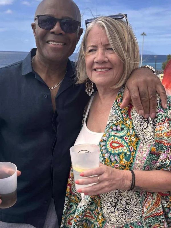 Smiling couple enjoying a drink outdoors by the water.