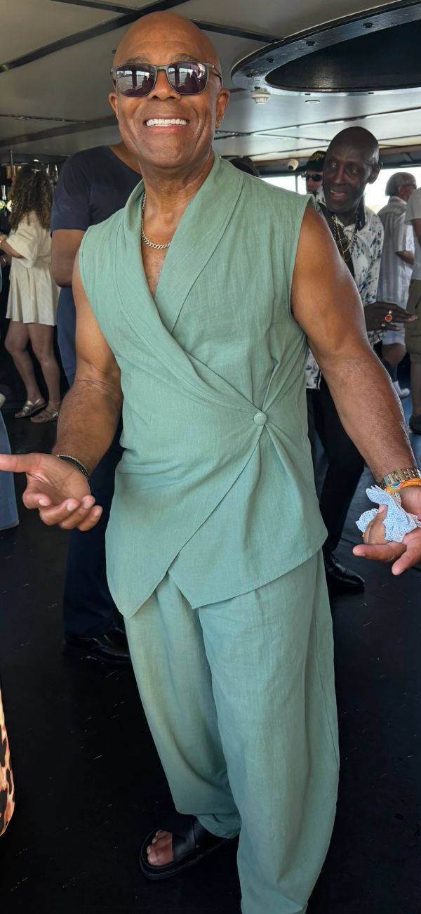 Smiling man in green sleeveless wrap suit and sunglasses.