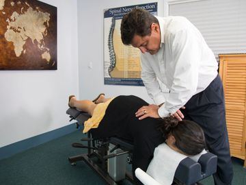 Chiropractor adjusting a woman's back in a clinic.
