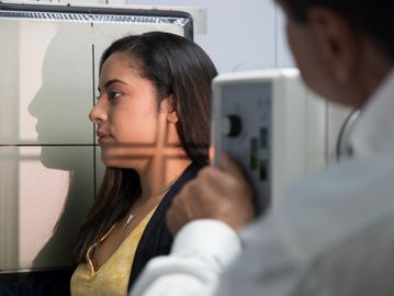 A woman undergoing an X-ray or facial scan by a medical professional.
