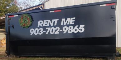 Large black rental container with a wreath and phone number.