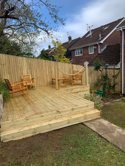 Wooden deck with chairs and a rope railing in a backyard.