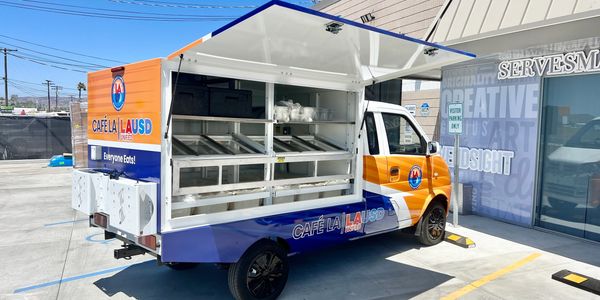 Mobile food truck parked outdoors with a serving window open.