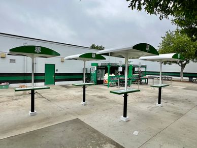 Outdoor tables with green umbrellas at a dining area.