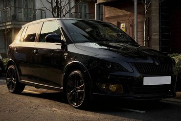 Sleek black hatchback car parked on a sunlit street.