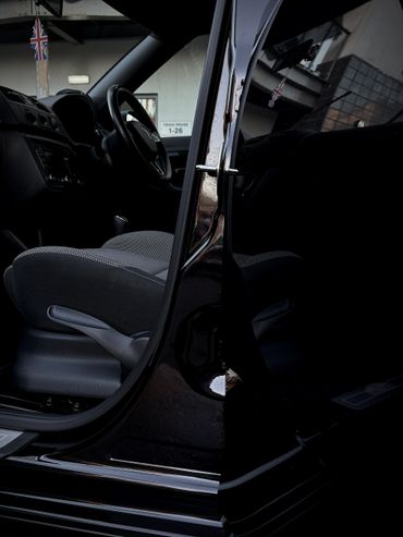 Open car door showing black interior and seat details.