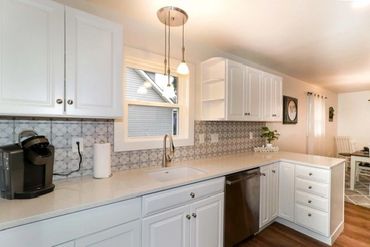 Bright kitchen with white cabinets and patterned backsplash.