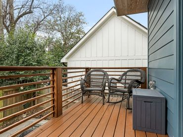 Cozy wooden deck with two wicker chairs and a small storage box.