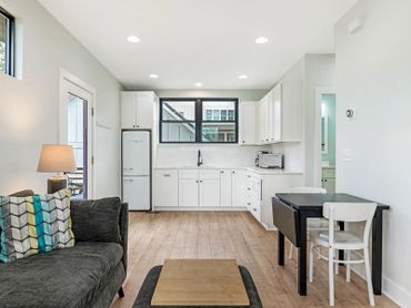 Bright, modern kitchen and dining area with white cabinets and wooden floors.