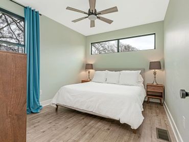 Cozy bedroom with white bedding, wooden floors, and blue curtains.