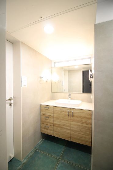 Modern bathroom vanity with wooden cabinets and a large mirror.