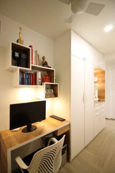Modern study area with wooden desk, white shelves, and a computer.