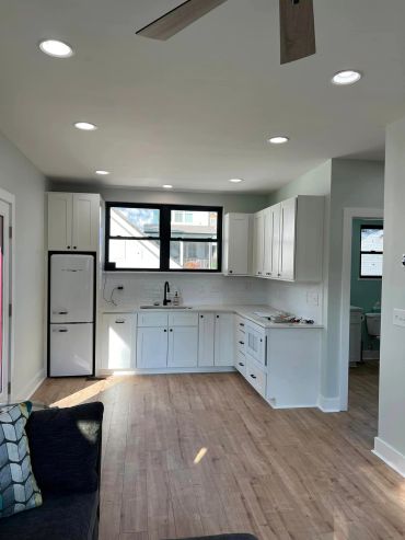 Modern kitchen with white cabinetry and wooden flooring.