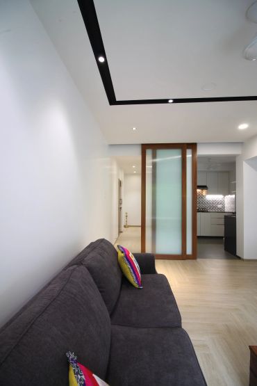Modern living room with a dark sofa and frosted glass sliding door.