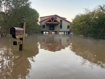A house and mailbox partially submerged in floodwater.