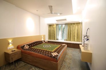 Minimalist bedroom with wooden furniture and patterned bedspread.