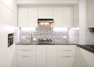 Modern kitchen with white cabinets and patterned backsplash.
