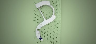 Top view of a winding white structure on a green terrain with scattered vertical elements.