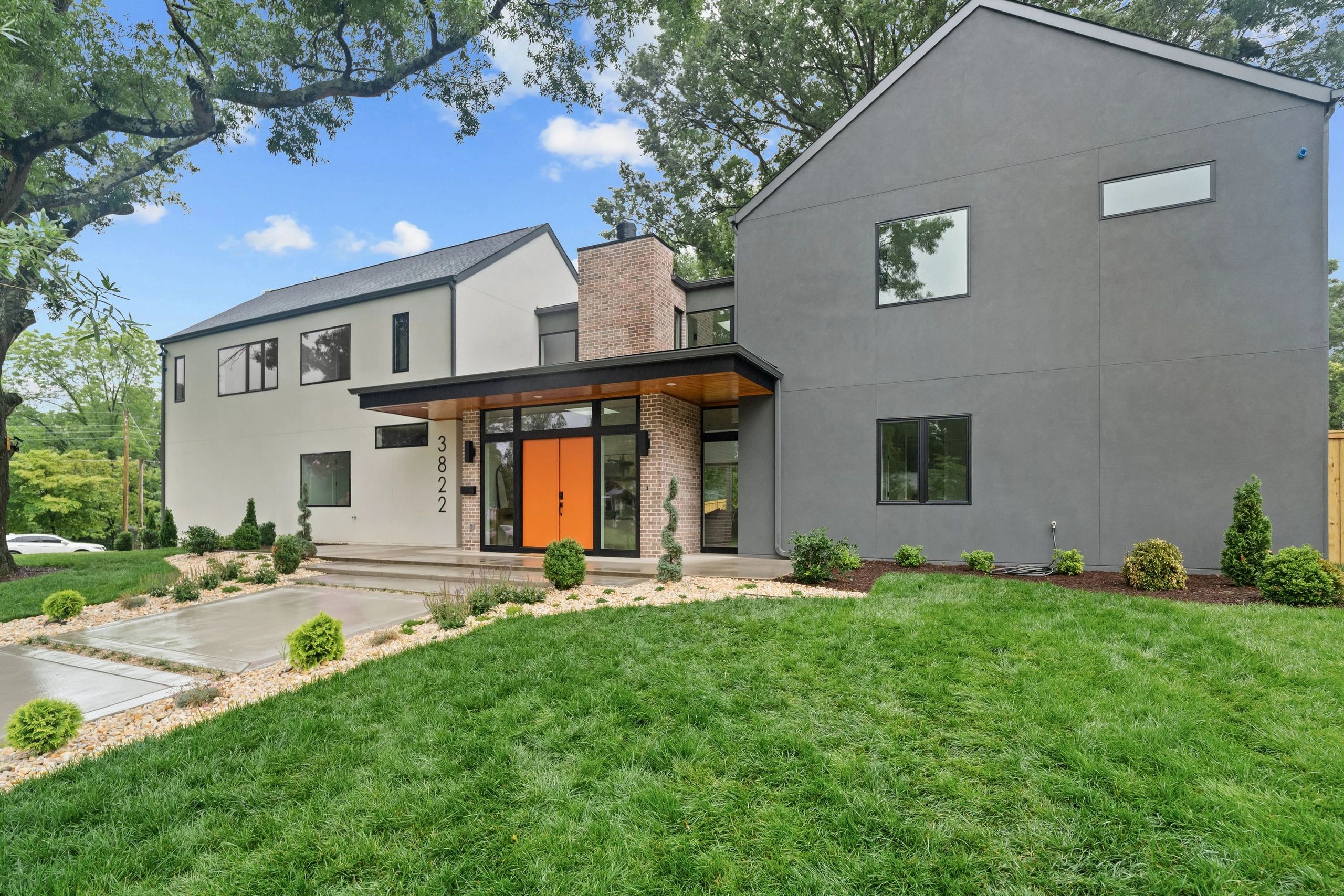 Modern two-story house with gray and white exterior and bright orange front door.