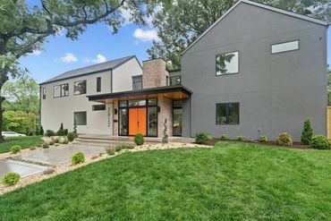 Modern two-story house with gray and white exterior and bright orange front door.