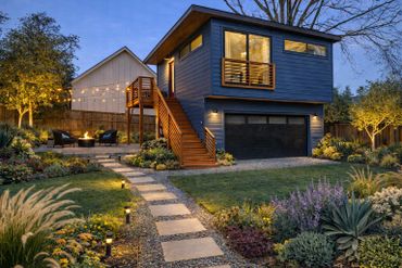 Modern backyard with cozy fire pit and stylish blue guesthouse.