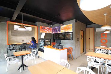 Modern cafe interior with geometric chairs and a single customer enjoying a drink.