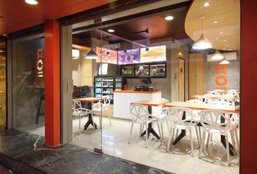 Modern cafe interior with geometric white chairs and orange tabletops.
