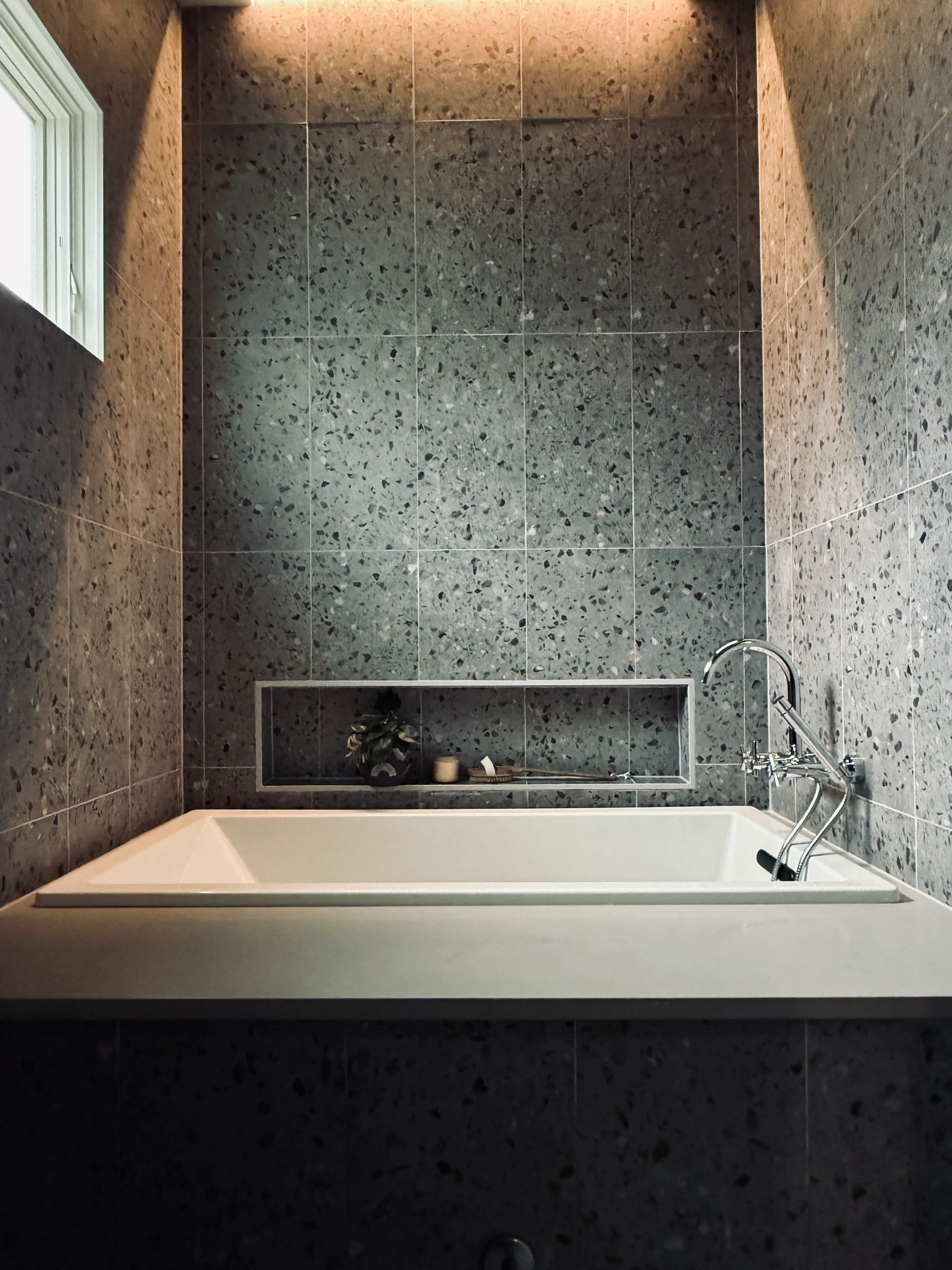Modern bathroom with terrazzo tiles and a white bathtub.