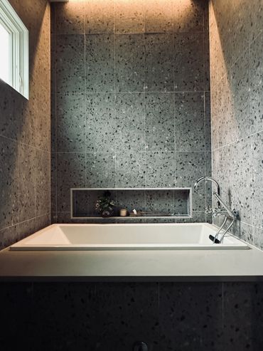 Modern bathroom with terrazzo tiles and a white bathtub.